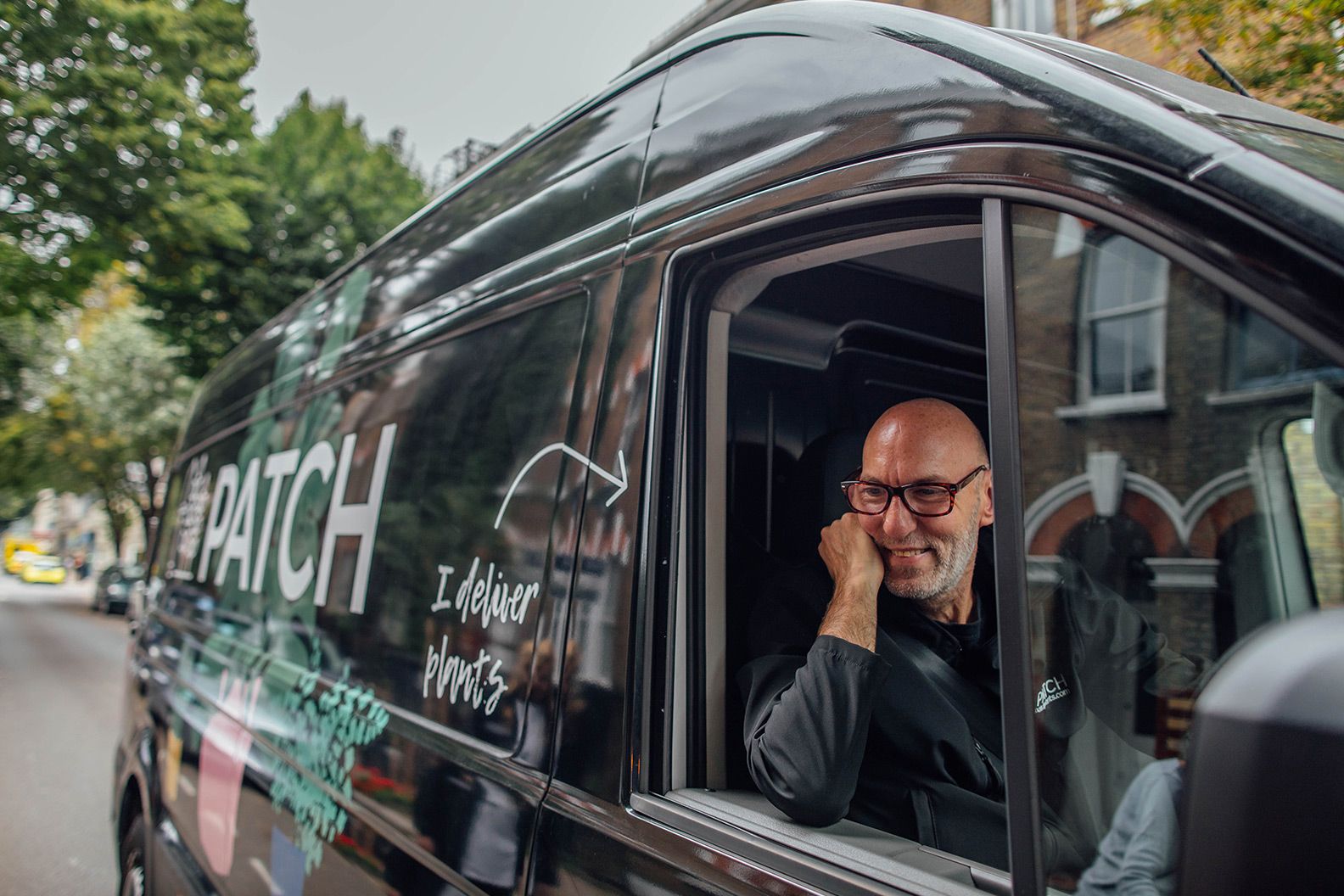 Patch delivery driver in a black branded delivery van